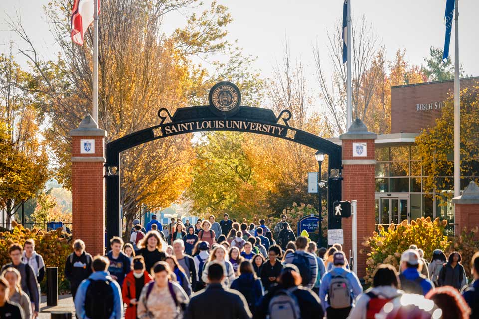 Crowd of students walking through the Saint Louis University gate near the student center