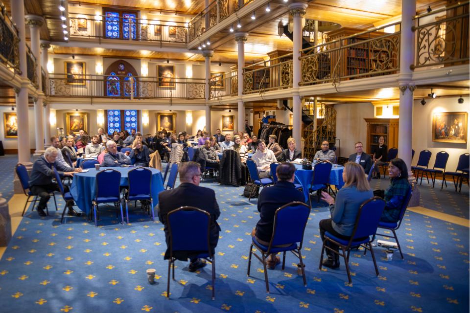 A Dialogue on Dimensions of Dignity a woman in the middle of a row of people speaks to a large crowd of people