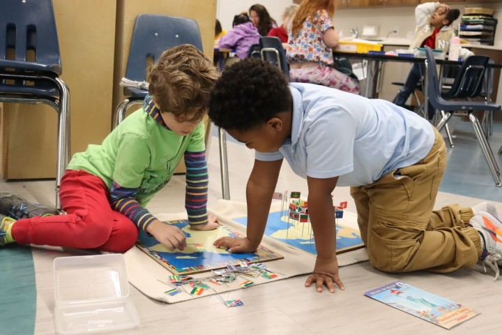 children in a classroom looking at a map
