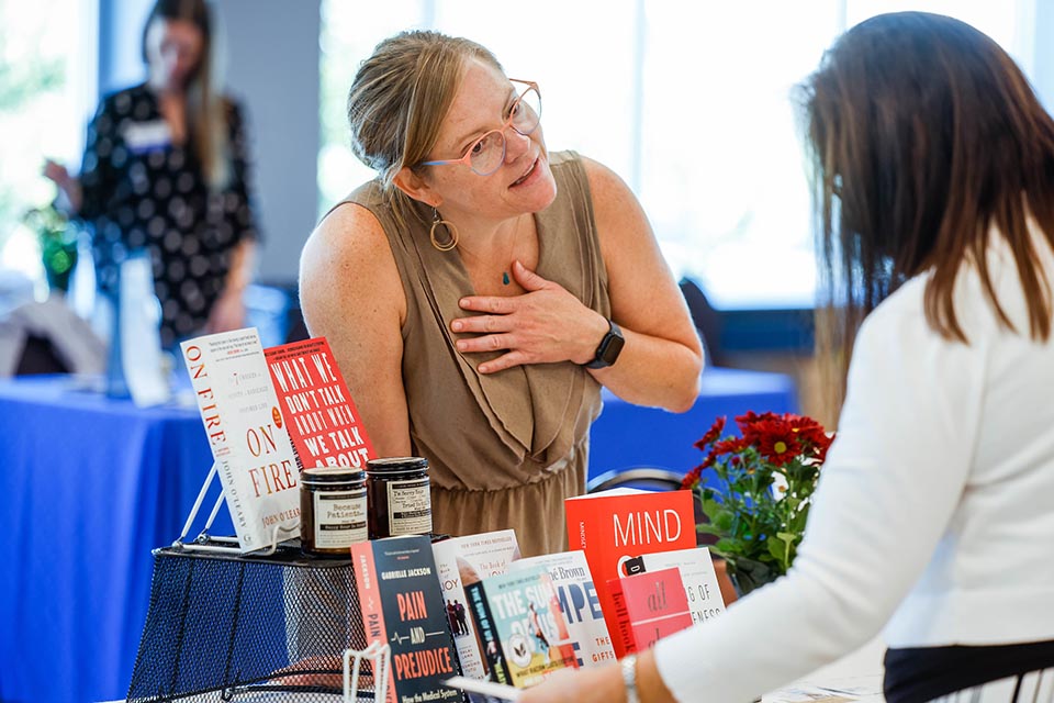 Employee at a book fair in front of a table of books