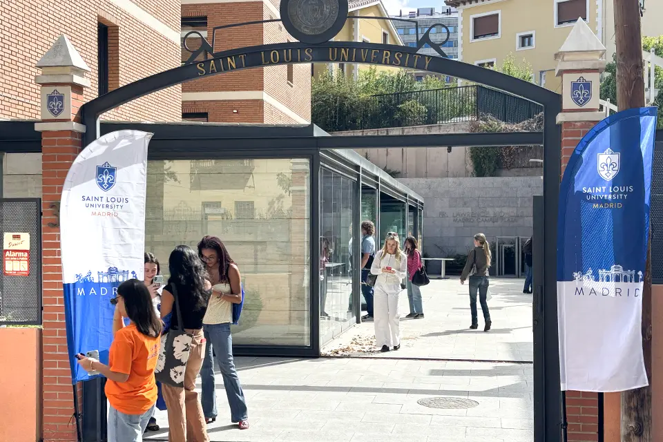 Two banners with university logo on both sides of entrance with an arch that reads “Saint Louis University”. Students can be seen in interior patio past the entrance.