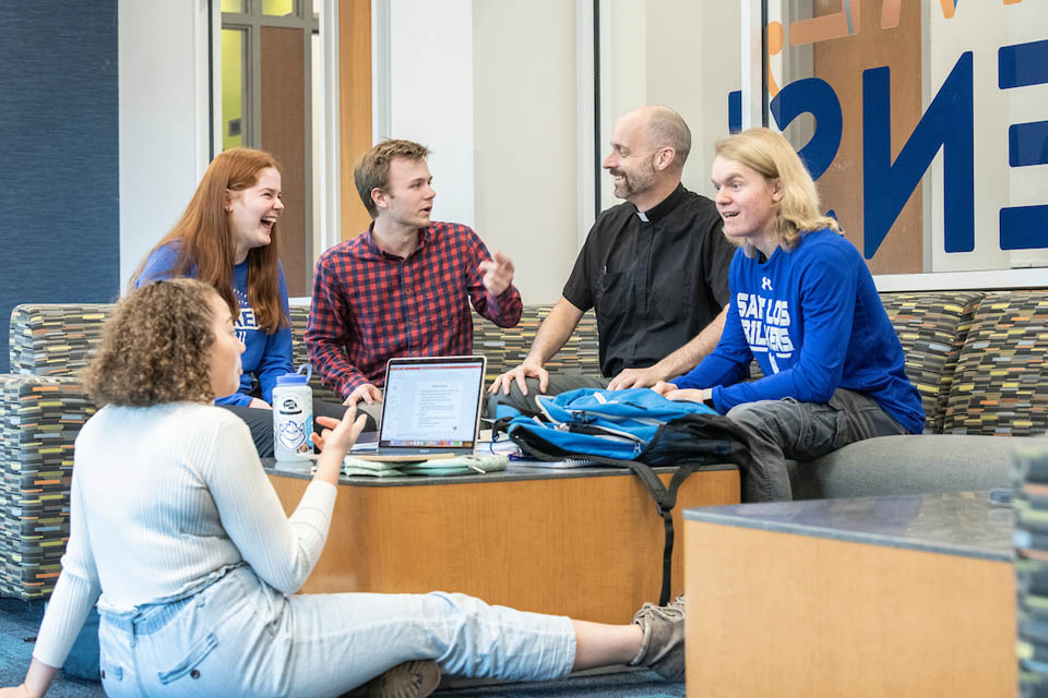 Fr. Laramie laughs with undergraduate students