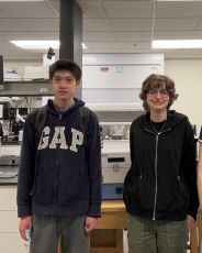 Students stand in front of their poster project.